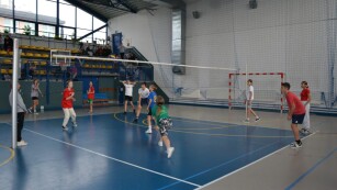 uczniowie grający w siatkówkę na sali gimnastycznej
